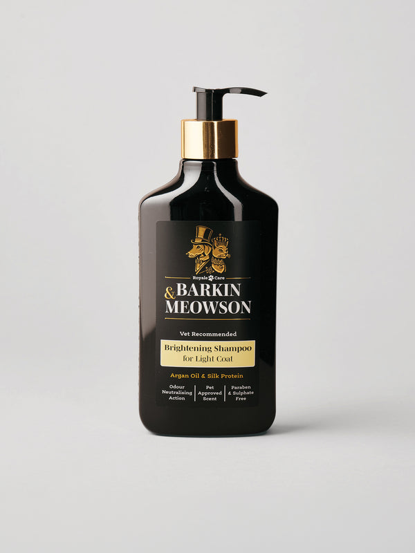 A bottle of Barkin & Meowson Brightening Shampoo for Light Coat, in a matte black bottle with a gold collar and black pump, on a light gray background.