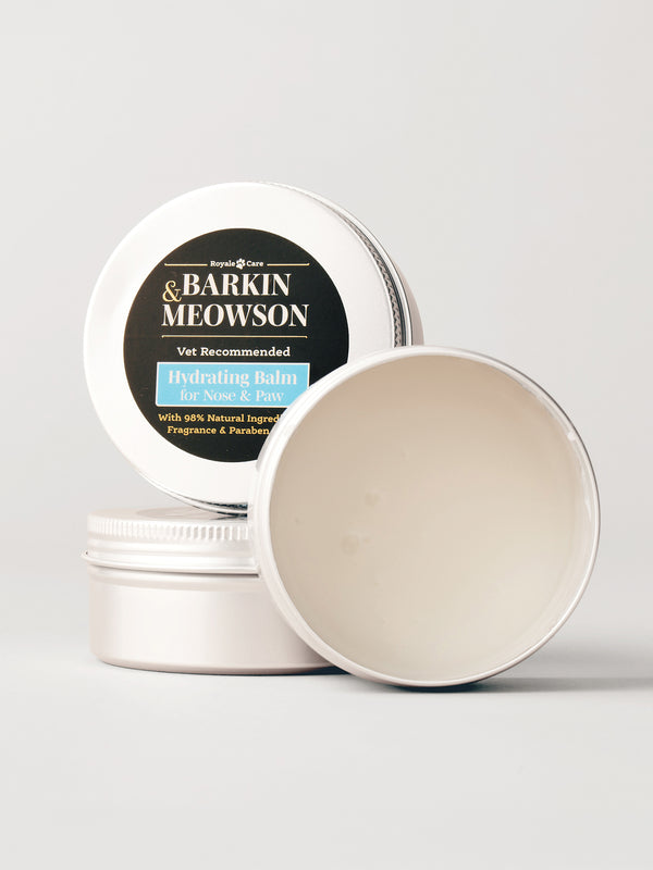 A round metal tin of Barkin&Meowson Hydrating Balm for Dogs & Cats, with one tin open to show the cream-colored balm inside and another tin standing behind showing the label.